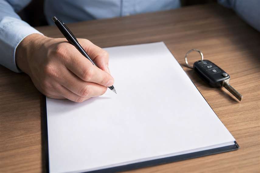 Pessoa assinando documento sobre uma mesa