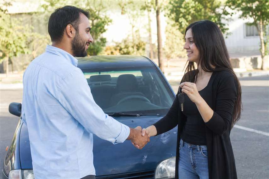 Duas pessoas negociando a compra de um carro usado